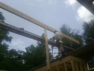 Carpenter setting a ridge beam over a new addition frame — Ice Dam Removal by Roofing Brothers in Selbyville