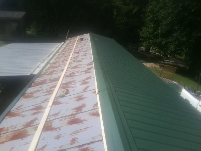 Old rusted panels beside newly installed green metal roofing — Wind Damage Roof Repair by Roofing Brothers in Selbyville
