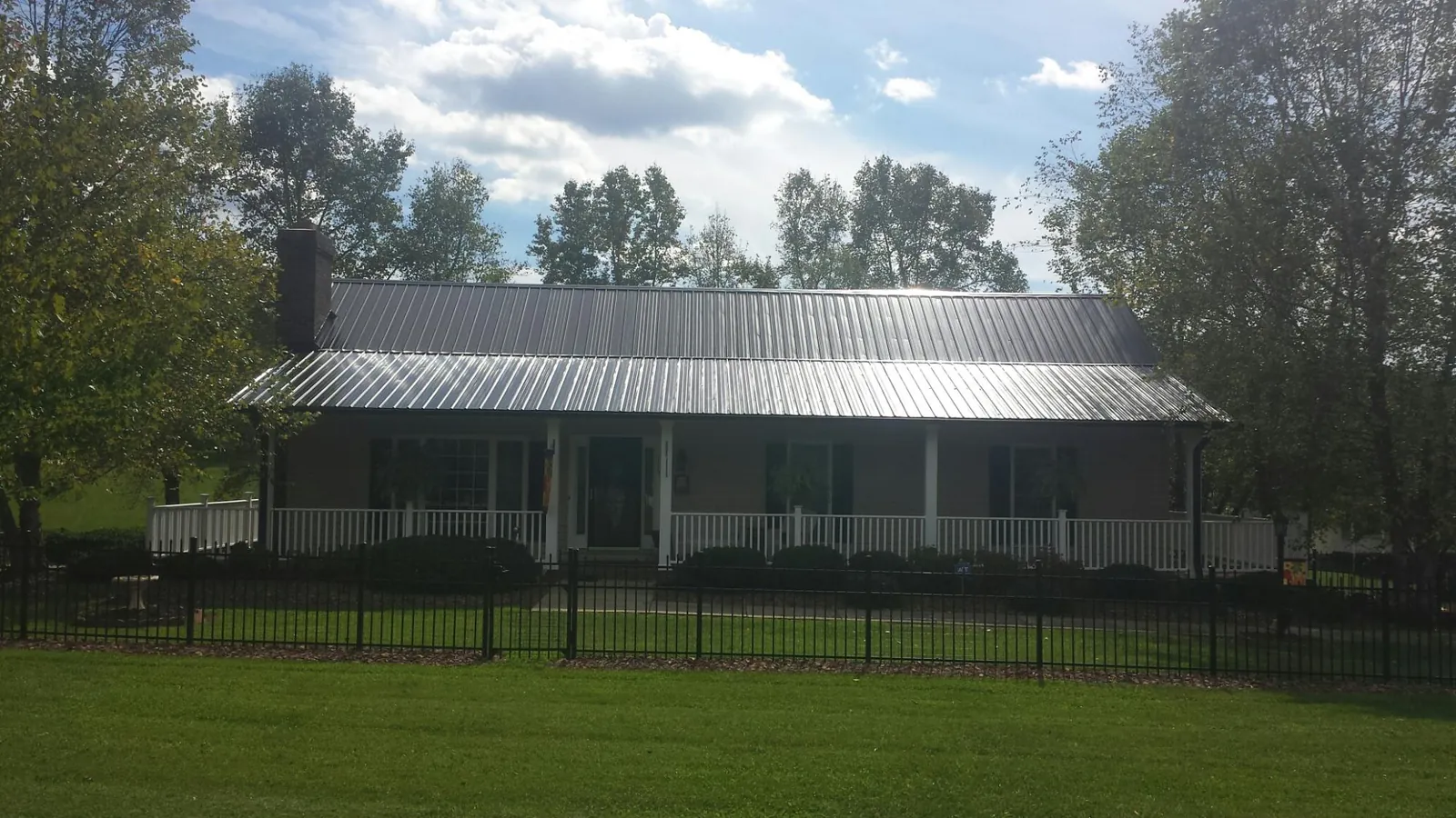 Gray metal roof on a brick ranch with a full width front porch — Gutter Guard Installation work by our crew in Selbyville
