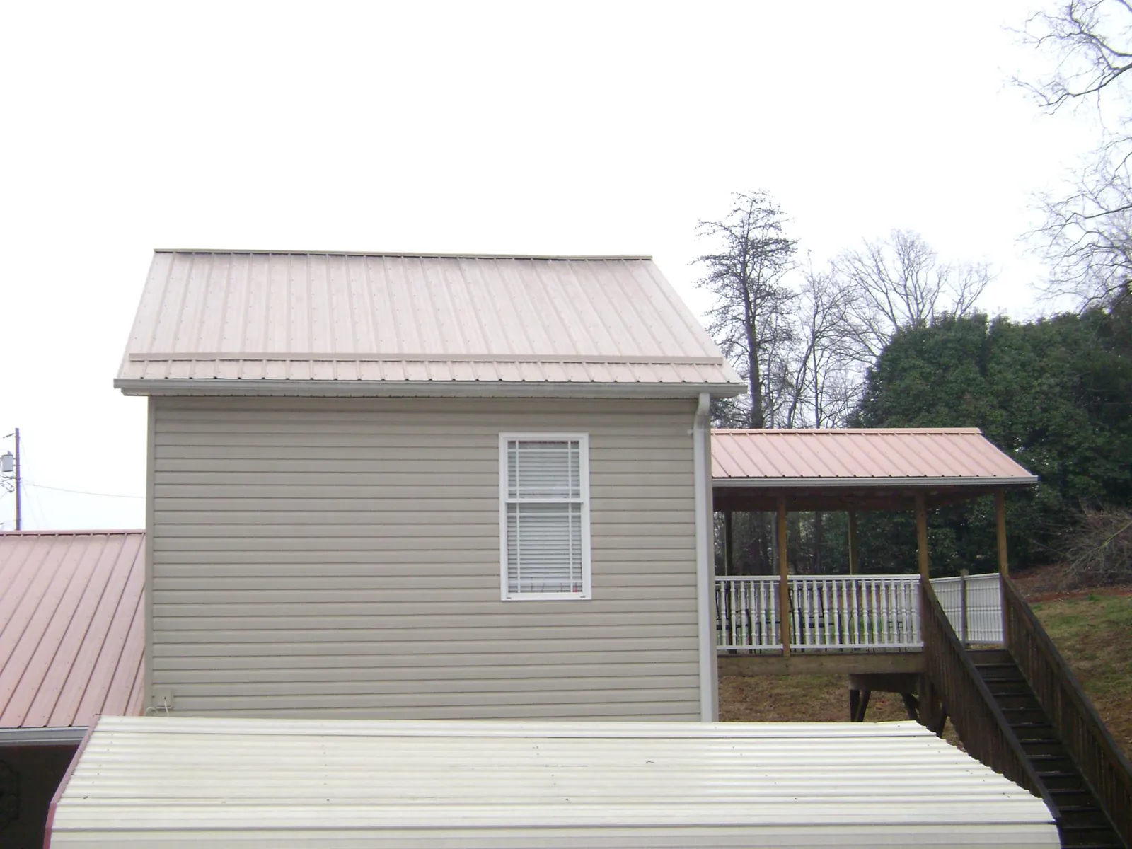 Tan metal roofs on a two story addition and attached porch, from a Roof Replacement job in Selbyville