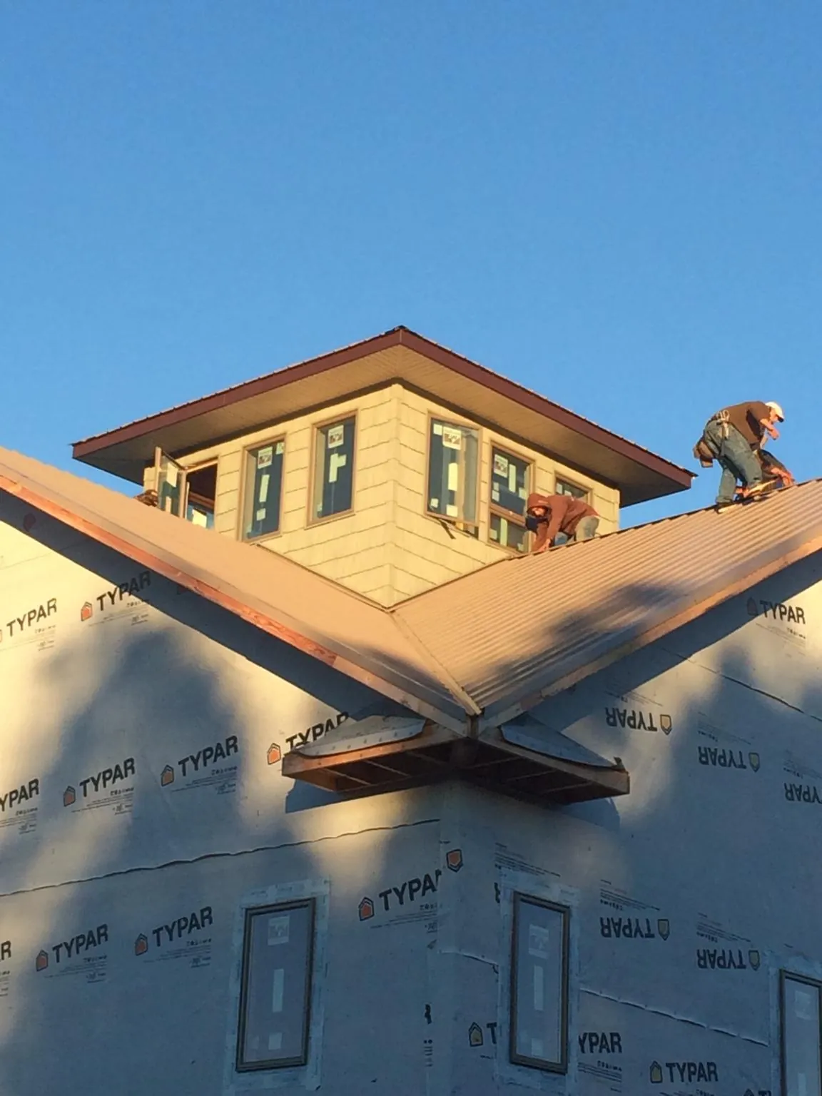 Roofers working around a rooftop cupola on a new metal roof at sunset — Roof Waterproofing in Selbyville by Roofing Brothers